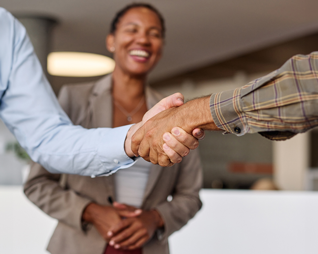 woman smiling while two people shake hands